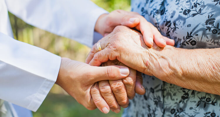 A group of dementia caregivers joining hands in a support group.