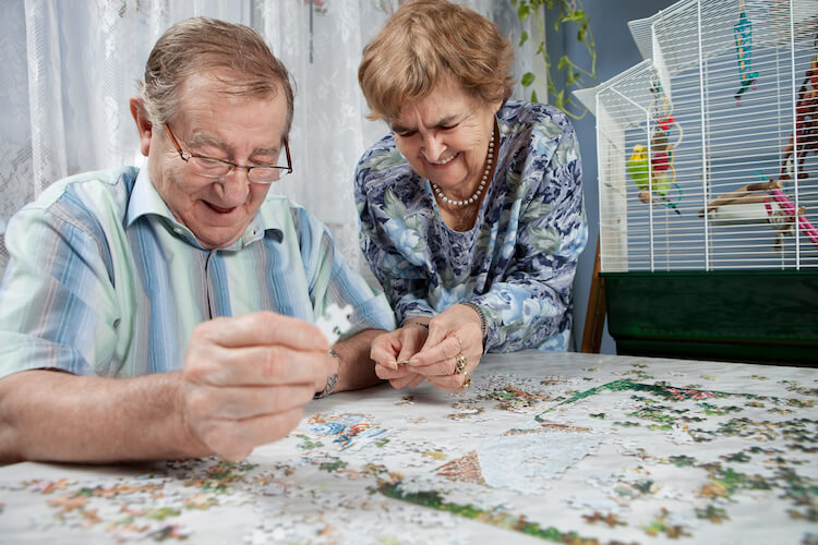 A senior couple completing a puzzle at a senior living community.