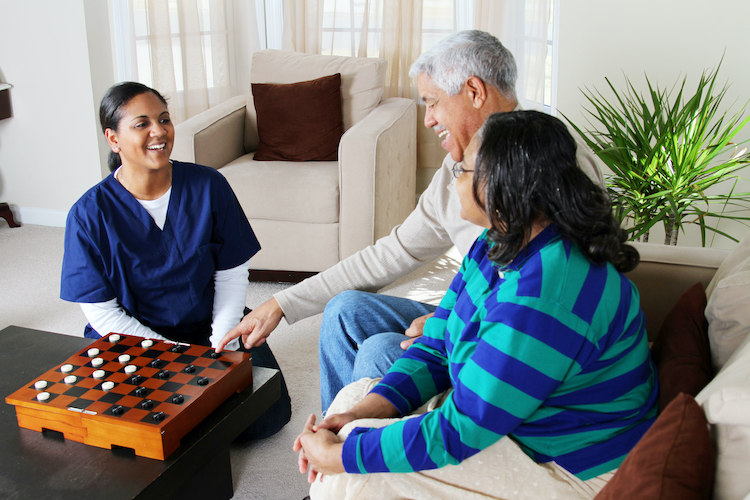 At-home senior care nurse providing support for seniors by playing a game.